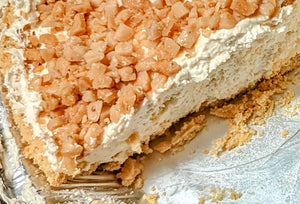 A closeup slice of salted caramel pie with a graham cracker crust and a crunchy topping of health toffee bits.